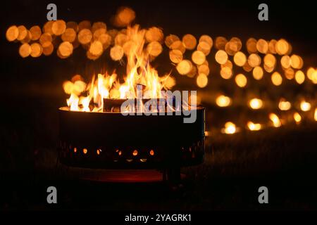 Lagerfeuer und Kerzen im Freien in der Landschaft. Das Lagerfeuer brennt in einem Garten. Konzepte: Gemütlichkeit, Reisen, Genuss der Natur. Stockfoto