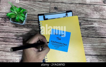 Konzept „mit den Grundlagen beginnen“ Schreiben Sie auf Haftnotizen, die auf Holztisch isoliert sind. Stockfoto