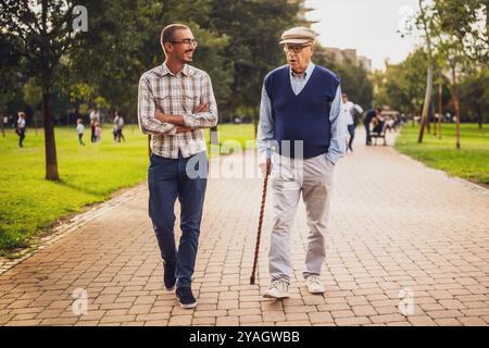 Glücklicher Großvater und Enkel gehen und reden im Park. Stockfoto