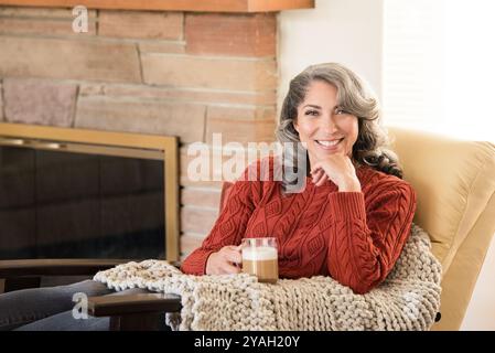 Gemütliche Frau, die zu Hause mit Kaffee lächelt Stockfoto