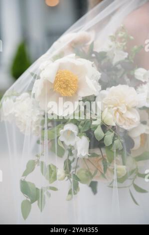 Braut mit weißem und grünem Brautstrauß unter Schleier Stockfoto