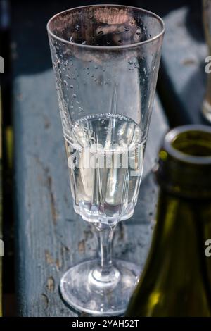 Ein hohes Flötenglas mit Wein an einem Poub-Tisch draußen im Sommer. Das Glas ist oben mit rotem Lippenstift verschmiert. Stockfoto