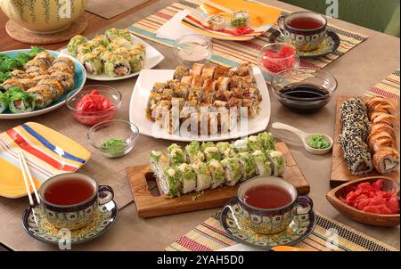 Sushi-Sets, Soße, Wasabi, Tee auf dem Partytisch. Essen und traditionelle asiatische Küche. Tischeinstellung. Stockfoto
