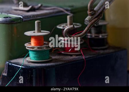 Bunte Fadenspulen auf einer industriellen Nähmaschine in Werkstattumgebung Stockfoto