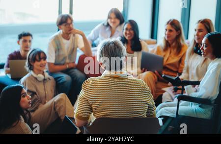 Eine generationenübergreifende Lerngruppe mit Schülern, die in einer gemeinsamen Sitzung die Vielfalt und den Wissensaustausch in einem modernen, hellen Ambiente hervorheben Stockfoto