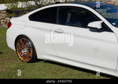 Weißer Sportwagen bmw m4 mit orangefarbenen Felgen auf grünem Gras Stockfoto