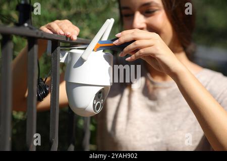 Frau, die eine wlan-Sicherheitskamera in einem Hausgarten installiert Stockfoto