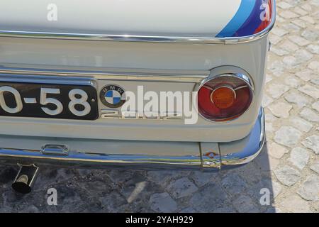 Nahaufnahme des Rücklichts und der Chromstoßstange eines klassischen bmw 2002, der auf einer Kopfsteinpflasterstraße geparkt ist Stockfoto