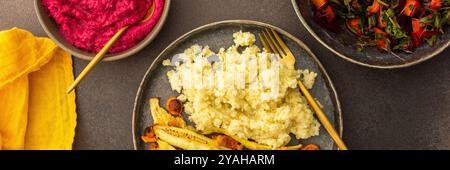 Genießen Sie ein köstliches vegetarisches Mittagessen oder Frühstück mit Hirse, gerösteter Zucchini und Karotten, einem frischen Salat mit saisonalem Gemüse und Kräutern, plus Stockfoto