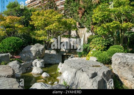 Fantastischer japanischer Garten mit Teich und Laterne, Kiefern und Wolkenkratzern in Disance und Felsen von Monaco Stockfoto