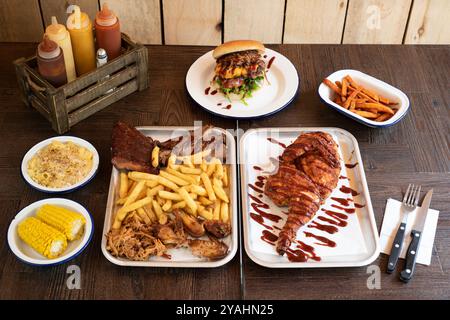 Grillgerichte im Restaurant, darunter BBQ-Hühnchen, Rippchen, Pulled Port, Beef Brisket Burger, Nachos und Pommes Frites Stockfoto