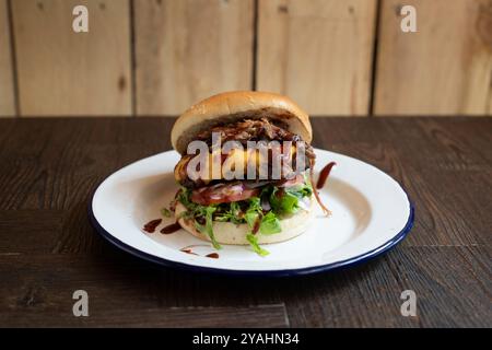 Badass Brisket Burger, ein Barbrust Burger mit Käse und Pulled Pork, serviert mit BBQ-Sauce und Salat Stockfoto