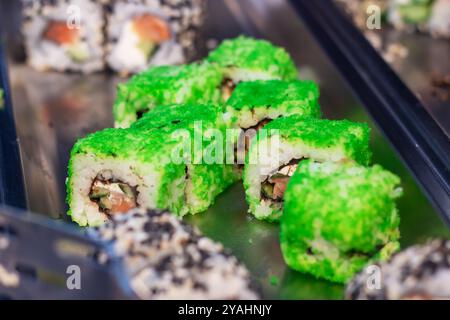 Dieses Bild zeigt eine Nahaufnahme einer Auswahl an farbenfrohen Sushi-Rollen, die elegant auf einem dekorativen Tablett angeordnet sind und deren Attraktivität zum Ausdruck bringen Stockfoto