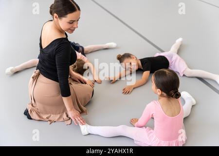 Die Trainerin der Ballettschule hilft jungen Ballerinas bei verschiedenen choreografischen Übungen Stockfoto