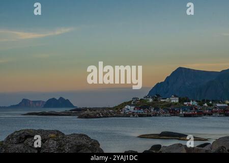 Bezauberndes Küstendorf der Lofoten bei Sonnenuntergang mit Bergkulisse und ruhigem Wasser Stockfoto
