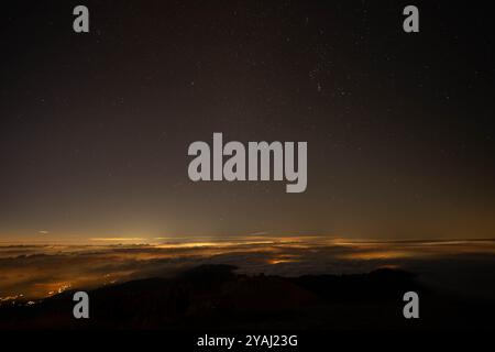 Sternenhimmel über Wolken, beleuchtet von fernen Stadtlichtern Stockfoto