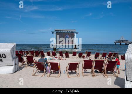 25.07.2024, Deutschland, Mecklenburg-Vorpommern, Heringsdorf - Europa - Urlauber sitzen am Strand des Kaiserbades Heringsdorf und beobachten ein Fil Stockfoto