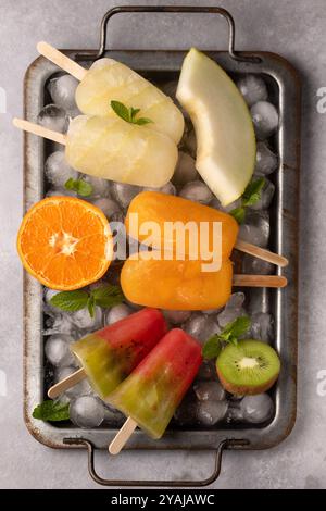 Verschiedene Fruchteis auf einem Stab Wassermelone, Kiwi, Melone und Mandarine Stockfoto