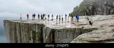 Preikestolen, Norwegen - 7. August 2022: Eine Gruppe von Personen, die sich anstehen, um ein Foto am Rand der Preikestolen Klippe, auch bekannt als Kanzel, zu machen Stockfoto