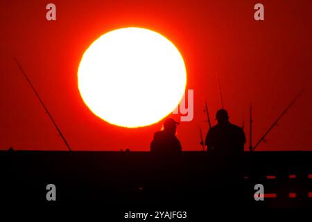 Isle Of Palms, Usa. Oktober 2024. Fisherman Silhouetten von einem dramatischen Sonnenaufgang werfen ihre Linien vor der Isle of Palms Pier am 14. Oktober 2024 in Isle of Palms, South Carolina. Klarer Himmel und warmes Wetter sind in der Prognose für das lowcountry. Quelle: Richard Ellis/Richard Ellis/Alamy Live News Stockfoto