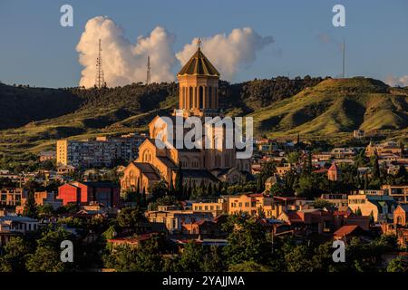 Die imposante Kathedrale der heiligen dreifaltigkeit tiflis georgien ragt an einem sonnigen Tag über die Altstadt vor dem Hintergrund grüner Hügel Stockfoto