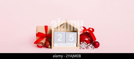 25 dezember. Weihnachtskomposition auf farbigem Hintergrund mit einem Holzkalender, mit Geschenkbox, Spielzeug, Kugel-Kopierraum. Stockfoto