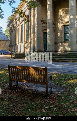 Ein hölzerner Sitz auf dem Gelände der Saltaire United Reformed Church in Yorkshire. Dieses denkmalgeschützte Gebäude befindet sich im viktorianischen Dorf Saltaire. Stockfoto