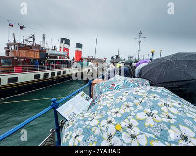 Passagiere, die an einem sehr nassen Tag auf eine Fahrt mit dem Waverley Raddampfer am Pier in Swanage, Dorset, England, warten Stockfoto