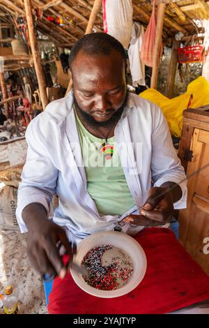 Lokaler Händler, der Souvenirs mit Perlen herstellt, um sie an Touristen auf dem Markt am Diani Beach, Mombasa, Kenia, Afrika, zu verkaufen Stockfoto