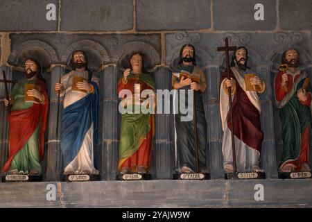 Sechs von 12 polychromen Apostelstatuen, die 1721 in Holz gemeißelt wurden und den Eingang einer bretonischen Kirche, L’Eglise Saint Sauveur, in Le Faou, Finistère, Bretagne, flankieren. Frankreich. Die Namen der Apostel sind auf den Sockeln unter ihren Füßen in bretonischer Sprache handgemalt. Die Statuen wurden kürzlich restauriert und neu gestrichen. Stockfoto