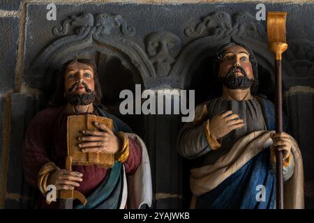 Der Heilige Paulus von Tarsus, bekannt als Paulus der Apostel (links), und der Heilige Jakobus, Sohn des Alphaeus. Köpfe und Oberkörper von zwei von 12 polychromen Apostelstatuen, die 1721 in Holz gemeißelt wurden und den Eingang einer bretonischen Kirche, L’Eglise Saint Sauveur, in Le Faou, Finistère, Bretagne, Frankreich, flankieren. Zu den 12 Statuen gehört der heilige Paulus von Tarsus, der die Lehren Jesu verbreitete, aber keiner der 12 Apostel Jesu war; die Statuen enthalten keinen Judas Iskariot. Stockfoto