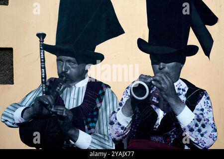 Traditionelle bretonische Musiker spielen auf einem Foto, das um 1920 aufgenommen wurde und später an der Seite eines Gebäudes in Le Faou, Finistère, Bretagne, Frankreich gezeigt wurde, einen Biniou (links) und einen Bombardement. Die Musiker stammten aus Rosnoën, einem Dorf südwestlich von Le Faou, im Gebiet Rouzig (Le Pays Rouzig oder Terroir Rouzig). Stockfoto