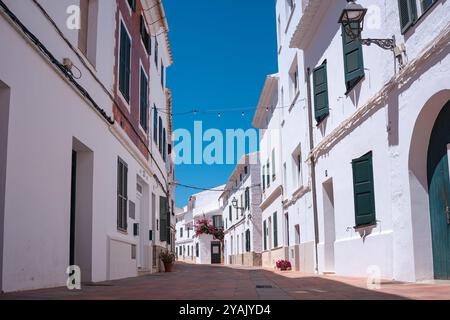 Traditionelle Gasse in einer spanischen Kleinstadt an einem sonnigen Sommertag mit klarem blauem Himmel. Beispiel der klassischen Architektur eines spanischen Dorfes auf Menorca Stockfoto