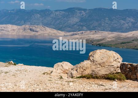 Malerischer Blick auf die felsige Küste und das blaue Meer mit Bergen im Hintergrund an einem sonnigen Tag. Stockfoto