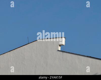 Ruhiger Minimalismus: Weiße Wand und Dach vor einem blauen klaren Himmel. Stockfoto