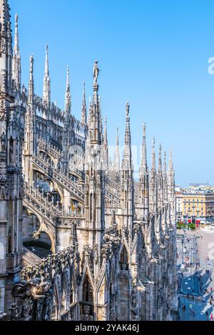 Vom Dach des Doms aus genießen Besucher einen atemberaubenden Blick auf Mailand. Die majestätischen Türme und die komplizierte Architektur sind vor einem klaren blauen Himmel zu sehen und schaffen eine atemberaubende Kulisse. Stockfoto