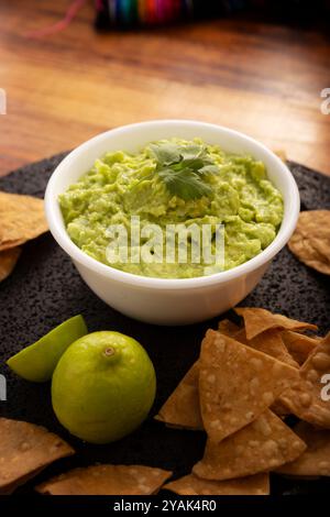 Guacamol. Avocado Dip Sauce, eine der vielen Arten, sie zu konsumieren, wird auf Tortilla Chips, auch Nachos genannt, verteilt. Mexikanisches Rezept für hausgemachte Soßen Stockfoto