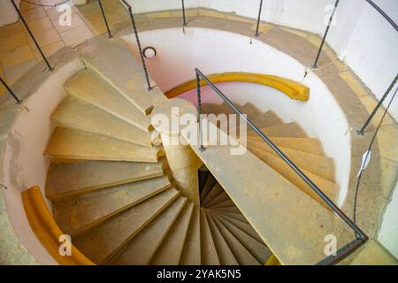 Eine atemberaubende Doppelspiraltreppe spiralisiert sich anmutig nach unten in einem modernen Gebäude. Die glatten Steinstufen und Geländer schaffen ein markantes architektonisches Merkmal. Stockfoto