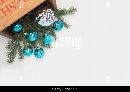 Große silberne und kleine blaue Weihnachtskugeln in einer alten Kiste mit Grün auf weißem Hintergrund. Stockfoto