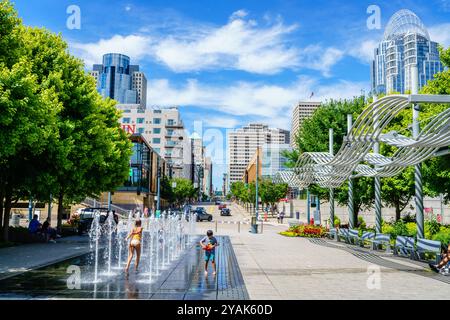 Cincinnati, Ohio, 30. Juli 2022: Kinder spielen im Springbrunnen im Smale Riverfront Park mit der Innenstadt von Cincinnati im Hintergrund Stockfoto