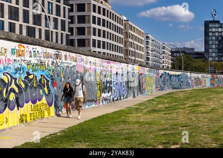 Die Menschen laufen auf der Rückseite der East Side Gallery, Teil der Berliner Mauer in Friedrichshain, Berlin, Deutschland Stockfoto