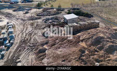 Aus der Vogelperspektive eines Lagerplatzes mit Schmutzhaufen, Felsen und Baumaterialien. Das kleine Gebäude ist von Stapeln von Betonblöcken und Streuungen umgeben Stockfoto