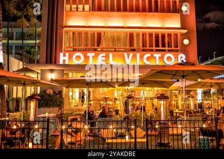 Miami, USA - 20. Januar 2021: Hotel Victor Americano Restaurant, Art Deco District Night Neonlicht in South Beach, Florida, Leute essen trinken Stockfoto