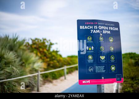 South Beach, USA - 17. Januar 2021: Nahaufnahme des Schilds Öffnungszeiten für Strand, Maske tragen in Miami, Florida während der Coronavirus-covid-19-Epidemie Stockfoto