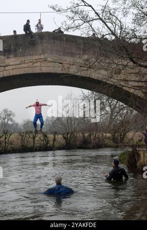 Mappleton, Derbyshire, Neujahrstag am Okeover Bridge Jump. Leute springen in den Fluss Taube, um das kommende Jahr zu feiern. Taucher im Vordergrund in Neoprenanzügen, um jedem zu helfen, der Hilfe braucht. England 2020 2020er Jahre UK HOMER SYKES Stockfoto