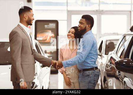 Autohändler Nach Erfolgreichem Geschäft Im Geschäft Mit Käufern In Handshake Stockfoto