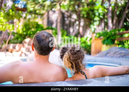 Junge Frau Mann romantisches Paar Schwimmen auf Stein Geländer Rand des japanischen Spa Pool mit bunten blauen Wasser in Japan Onsen Pool Stockfoto
