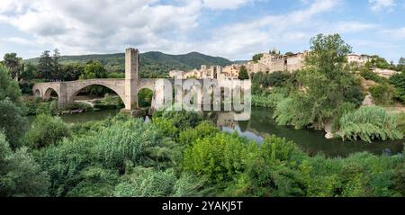 Fluss umgeben von viel Vegetation, über dem eine Brücke Zugang zu einer mittelalterlichen Stadt gibt Stockfoto