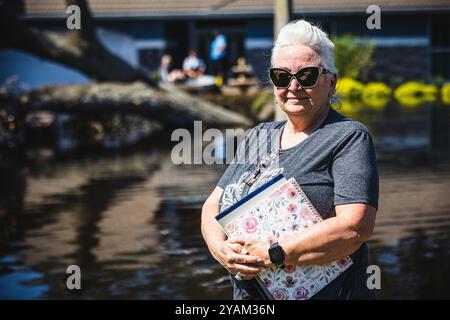 Zephyrhills, Florida, USA. Oktober 2024. Die Silver Oaks Community in Zephyrhills erlebte durch die historischen Regenfälle des Hurrikans Milton Rekordhochwasser. Das Haus der Familie Curtis war eines von 50 Häusern, die mit hüfthohem Wasser durchnässt waren, was eine Mischung aus Süßwasser und Abwasser ist, da die Kanalisation kaputt war, die durch die Ausrottung der 40 Meter hohen Eiche gefährdet wurde. Hier steht VICKIE CURTIS vor dem Haus, während ihre Familie rettet, was sie können. Quelle: ZUMA Press, Inc./Alamy Live News Stockfoto