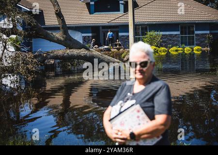 Zephyrhills, Florida, USA. Oktober 2024. Die Silver Oaks Community in Zephyrhills erlebte durch die historischen Regenfälle des Hurrikans Milton Rekordhochwasser. Das Haus der Familie Curtis war eines von 50 Häusern, die mit hüfthohem Wasser durchnässt waren, was eine Mischung aus Süßwasser und Abwasser ist, da die Kanalisation kaputt war, die durch die Ausrottung der 40 Meter hohen Eiche gefährdet wurde. Hier steht VICKIE CURTIS vor dem Haus, während ihre Familie rettet, was sie können. Quelle: ZUMA Press, Inc./Alamy Live News Stockfoto